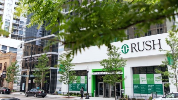 Exterior of RUSH South Loop as seen from across the street. It is a sunny day and a leafy tree branch hangs in the foreground.