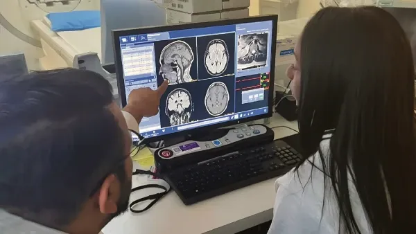 Two health care professionals review MRI images on a monitor