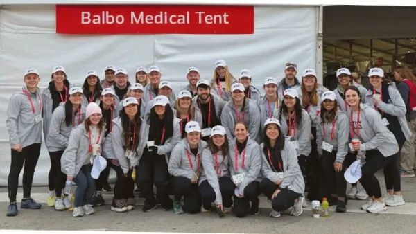 A group of people wearing matching sweatshirts in front of a white event tent