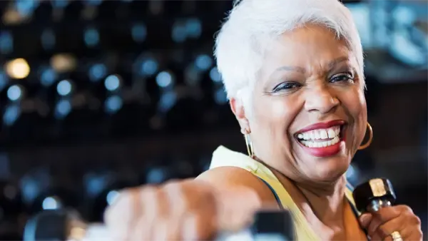 A smiling woman working out with weights