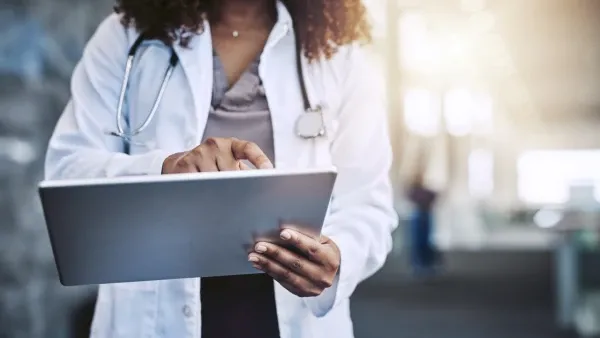 A heathcare provider wearing a white coat typing on a table
