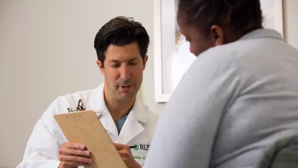 A doctor holding a clipboard consults with a patient