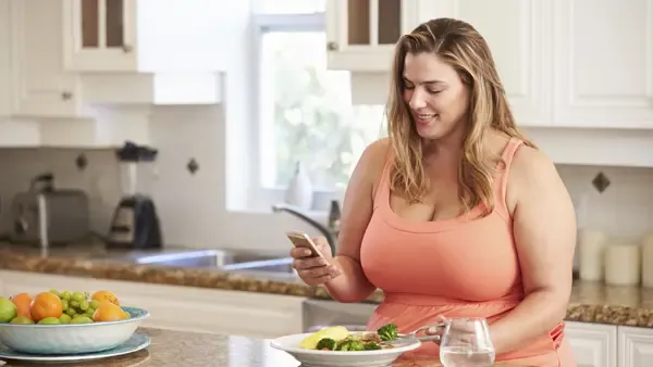 A woman sitting at a kitchen counter looking at her cellphone