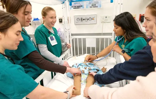 Nursing students gather around an infant mannikin in the simulation lab