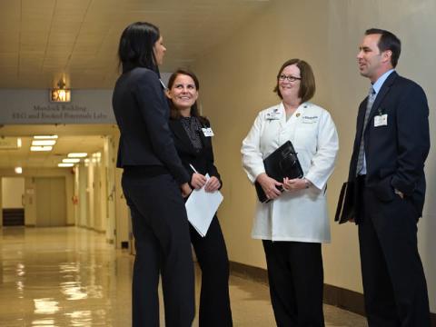 A RUSH U provider and health care administrators have a pleasant discussion in the hallway.