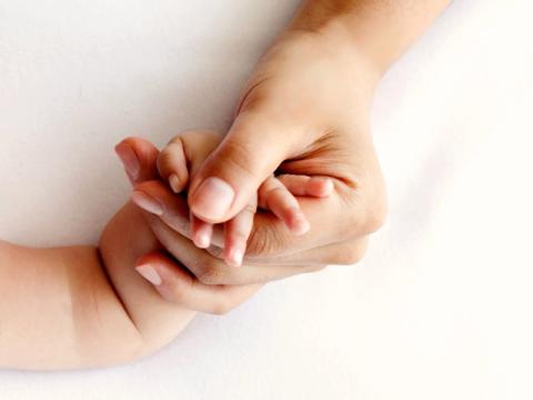 Close-up of a mother's hand holding her baby's hand