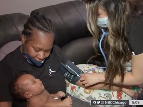 Still from a news video showing a mother holding a newborn while a nurse takes her blood pressure