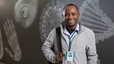 A smiling man in front of a mural showing radiographic illustrations