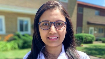 A smiling woman wearing a white coat