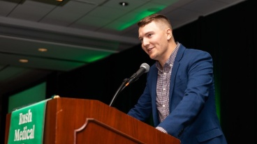 A speaker stands at a podium speaking into a microphone
