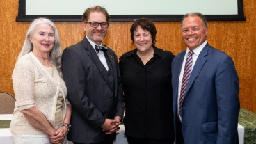 Four people standing together smiling