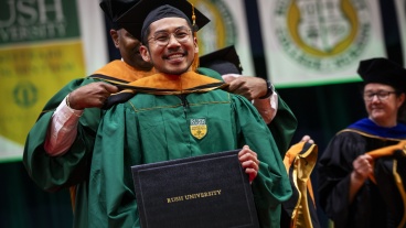 A student receives his diploma at the 53rd Commencement