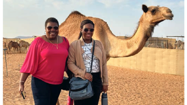 Two women take a selfie in front of a camera