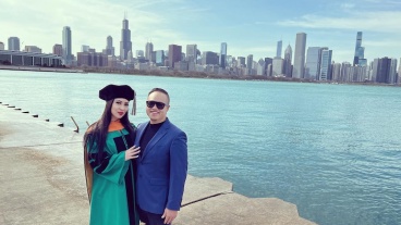 Two people standing by the Chicago lakefront, one wearinggraduation regalia