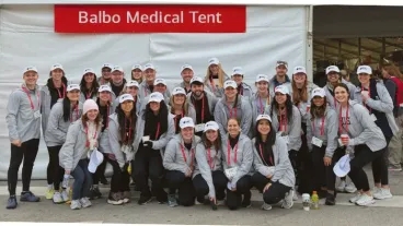 A group of people in matching sweatshirts pose in front of a white event tent with a sign saying Balbo Medical Tent