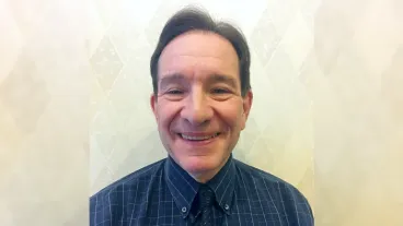 Headshot of David Margoli wearing a blue shirt and tie