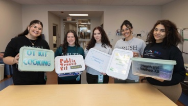 A group of five students in Rush University's Occupational Therapy Doctorate program hold up occupation kits.