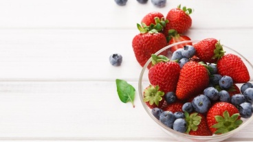 A glass bowl of blueberries and strawberries