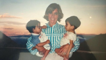 Vintage photo of a woman holding twin babies and smiling outdoors