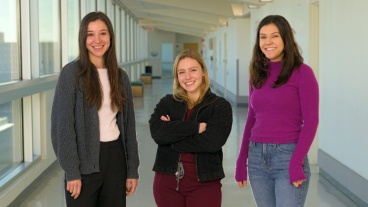 Three people standing together in a hospital corridor
