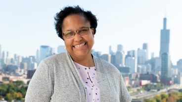 A smiling woman outdoors with the Chicago skyline visible in the distance