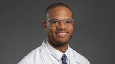 Headshot of Christopher Hicks, MD, wearing a white coat over a shirt and tie