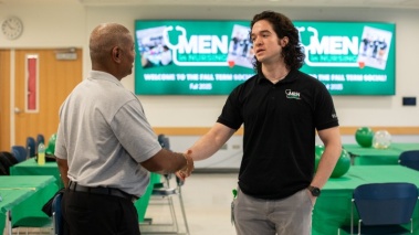Mateo Rey shakes hands with a faculty member at an event