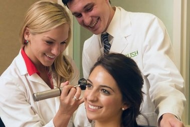Two audiology students conduct an ear exam on a patient