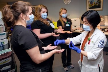 A hospital chaplain blesses the hands of health care providers