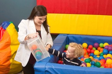Therapist with small child in a pool filled with colorful balls
